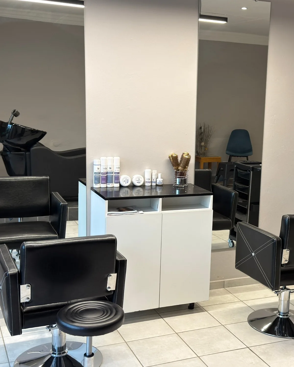 Black styling chairs, mirrors and a product cabinet in the hair studio in the Eloah building