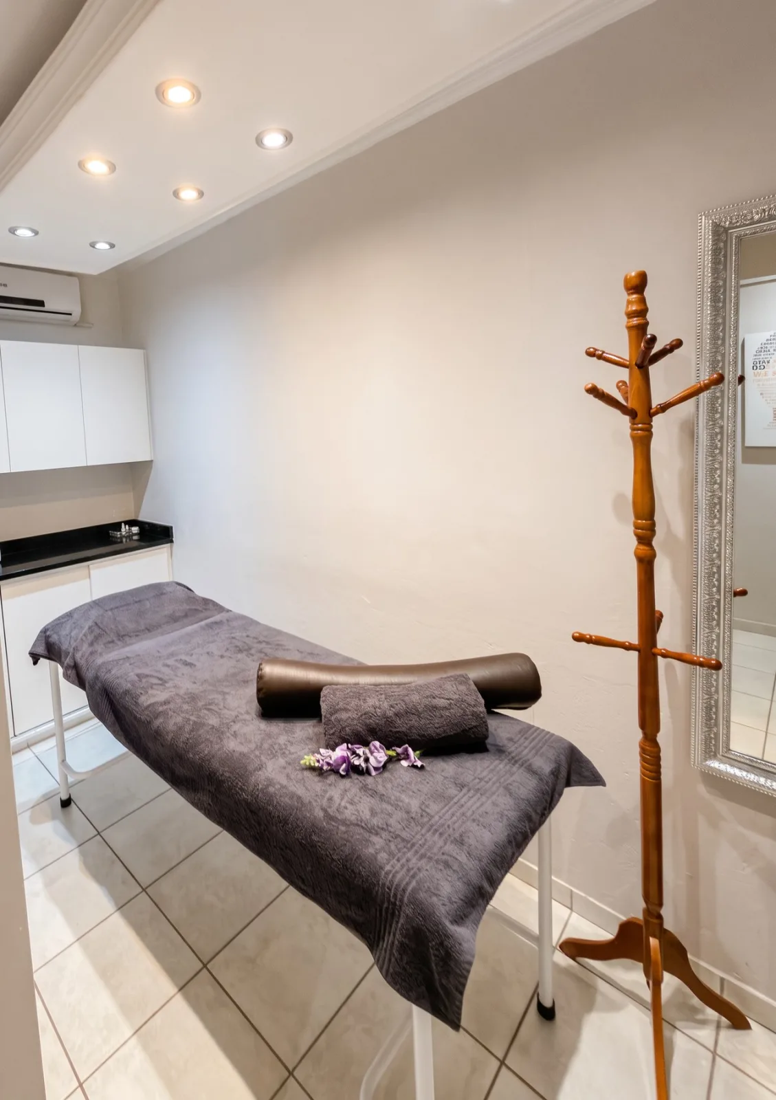 A calm Eloah treatment room with a dressed treatment bed and white cabinets